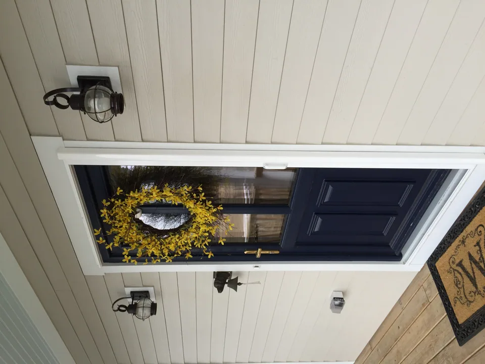 Retractable screen door fitted to a residential front entry, screen partially drawn
